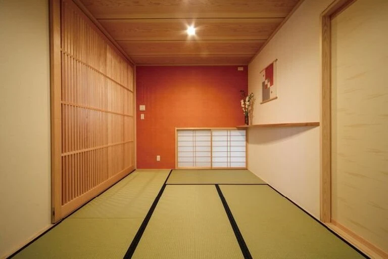 朱色のアクセントウォールと板張り天井の和室
